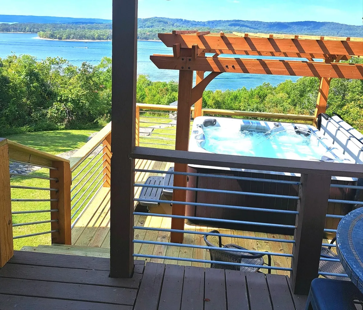 This image features a private hot tub set on a wooden deck, overlooking the tranquil lake. The scene is surrounded by natural greenery, capturing the golden hues of sunset as they play across the water. The atmosphere is intimate and secluded, ideal for relaxing while enjoying the view.