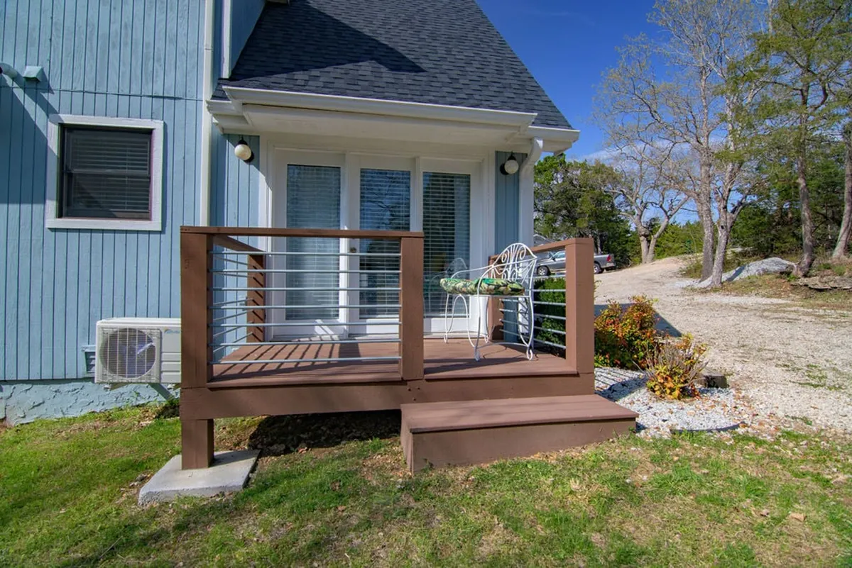 An outdoor deck with a railing, comfortable seating, and a flower arrangement offers a peaceful spot for morning coffee while admiring the lake view beyond.